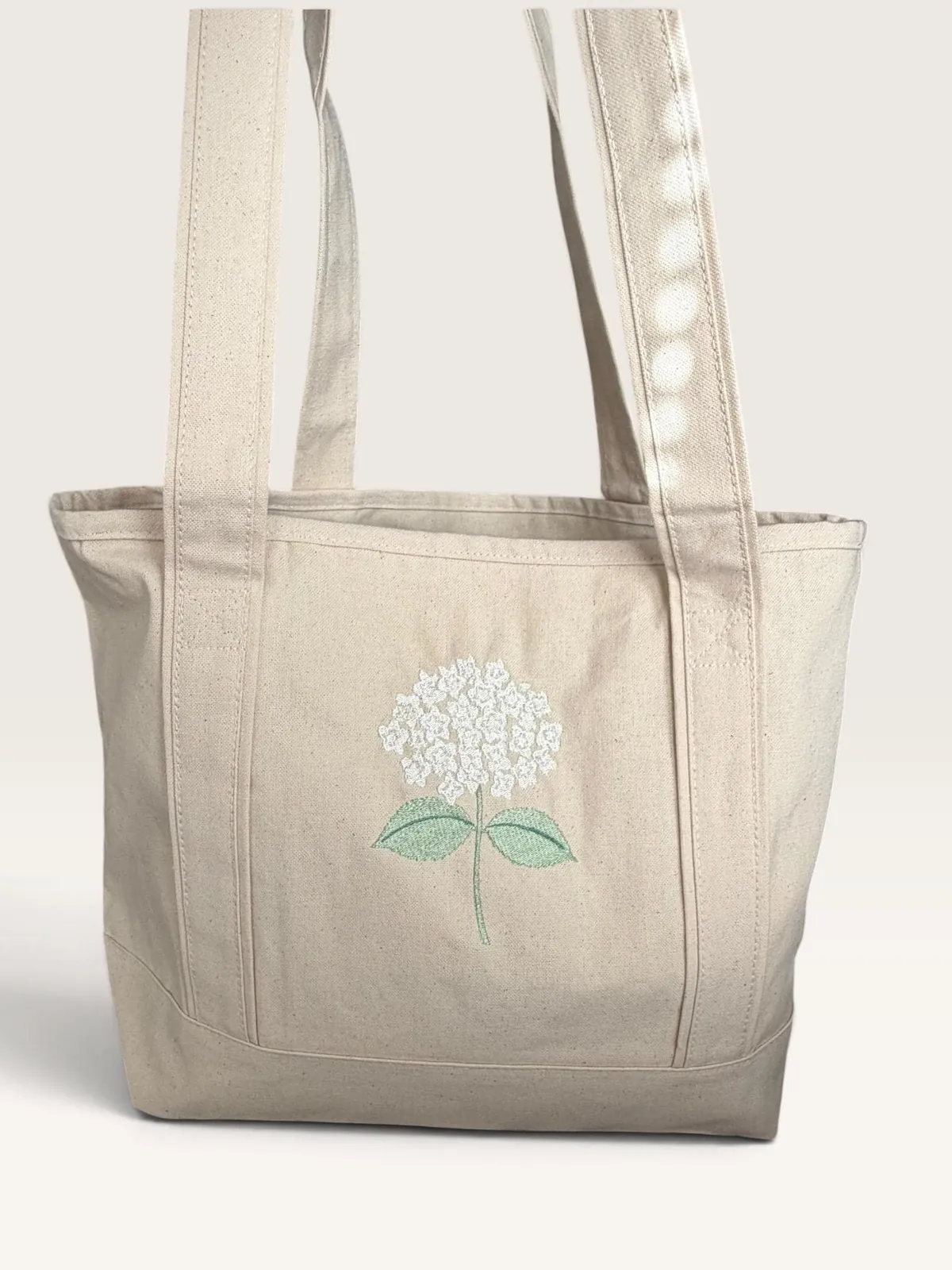 Canvas tote with an ivory embroidered hydrangea and soft green leaves